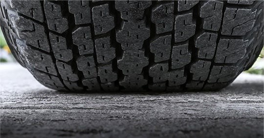 Close-up of a vehicle tire tread contacting the road, highlighting tread depth and tire condition.