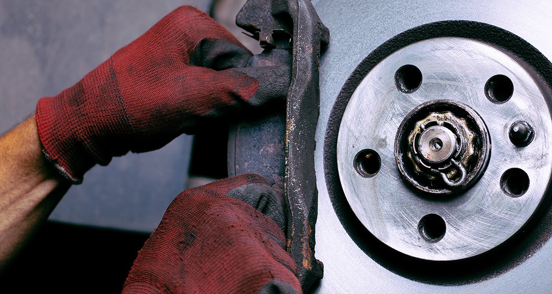 Mechanic inspecting a vehicle brake pad and rotor during brake service maintenance.